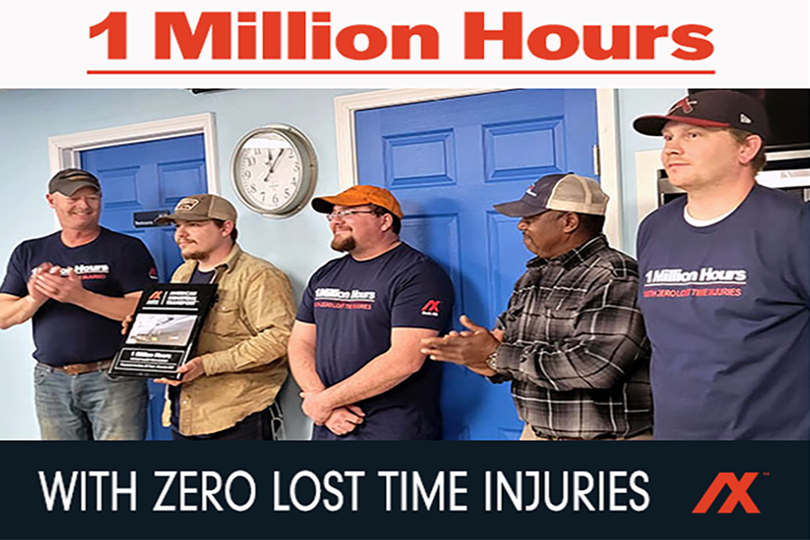 Group of employees celebrating the achievement of 1 million work hours with zero lost time injuries, showcasing teamwork and safety commitment. The event features a plaque presentation, with team members wearing branded shirts and hats, standing in front of blue doors.