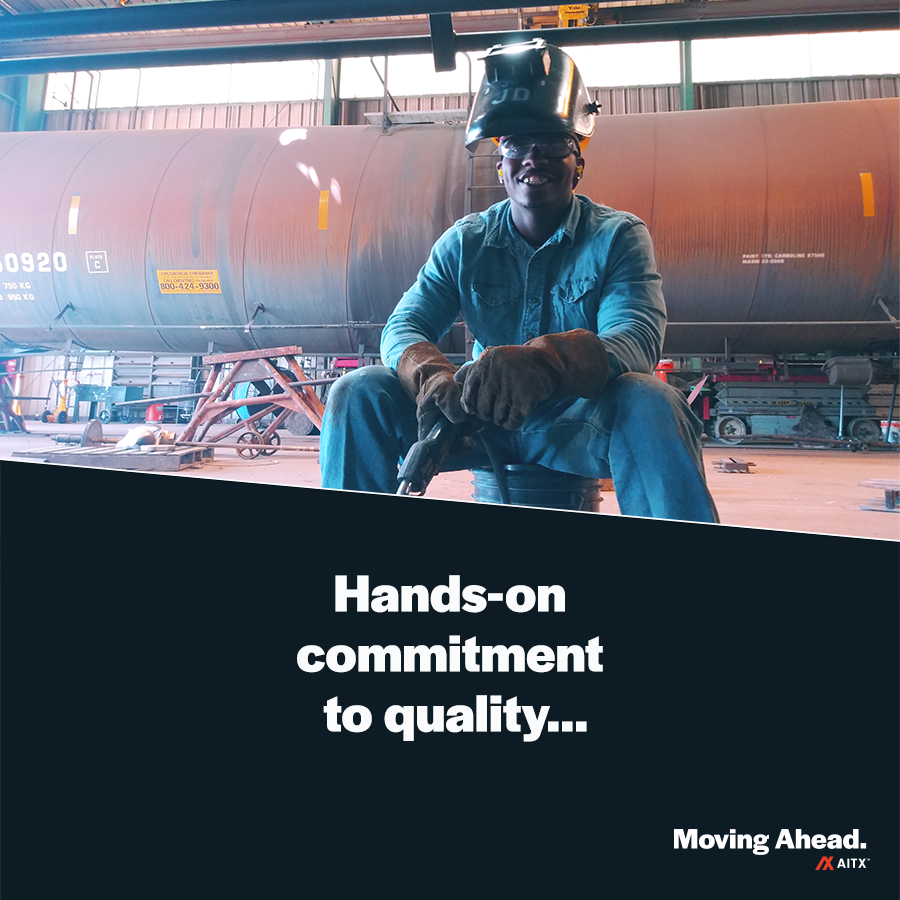 Welder in protective gear working on industrial equipment, demonstrating a hands-on commitment to quality in a manufacturing facility.