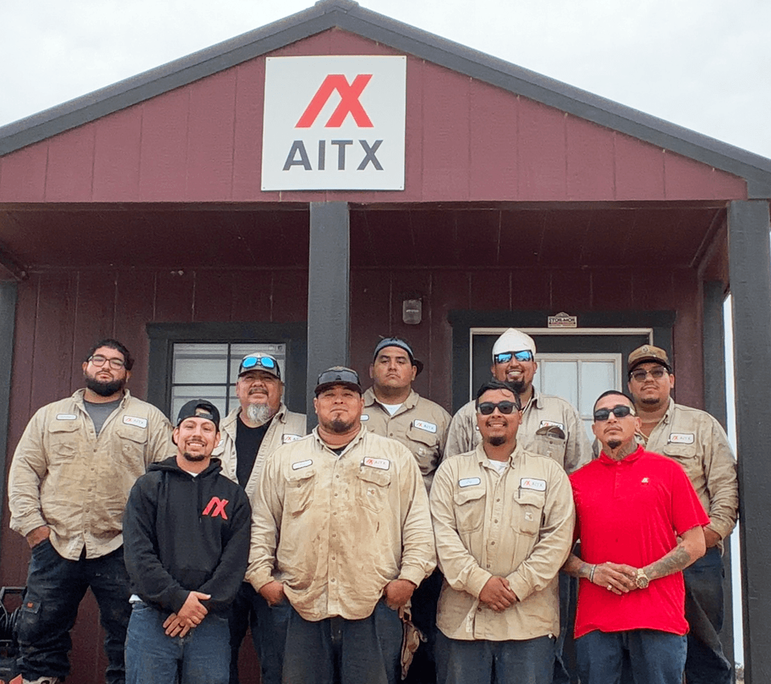 Group photo of AITX team members standing in front of their office, showcasing camaraderie and professionalism in the workplace. The team is dressed in work uniforms, emphasizing their dedication to service and collaboration.