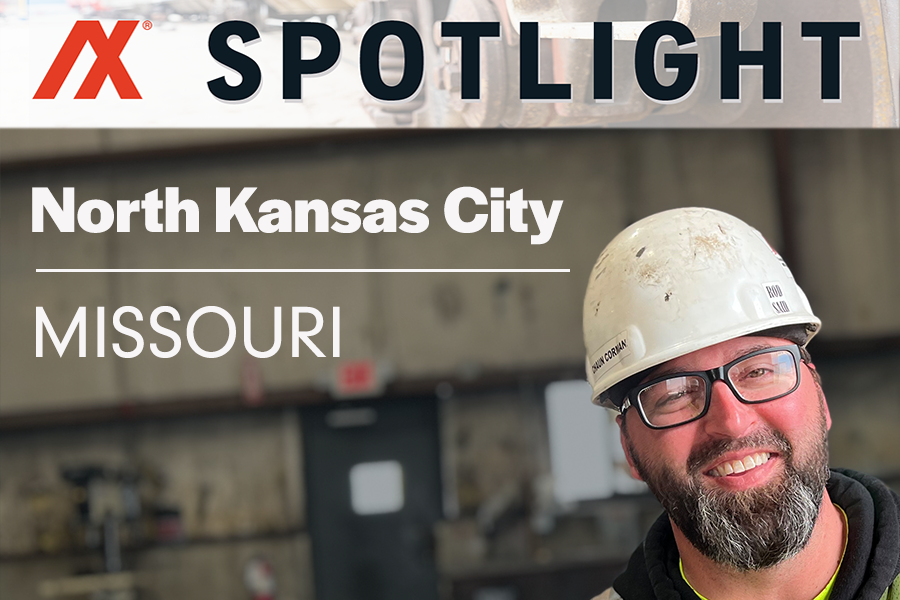 Portrait of a smiling male worker in a safety helmet and glasses, set in a North Kansas City, Missouri industrial environment, highlighting the local workforce and safety practices.