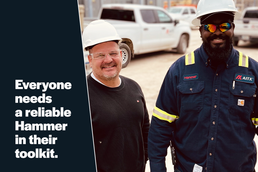 Two construction workers smiling on a job site, wearing hard hats and safety gear, with trucks in the background. The image emphasizes the importance of reliable tools, specifically highlighting the Hammer brand.