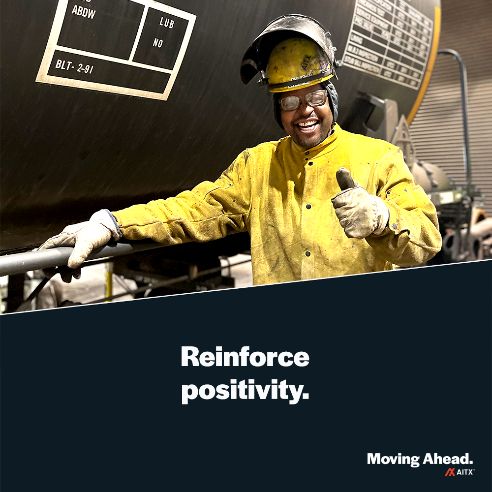 Worker in safety gear giving a thumbs up in a manufacturing facility, promoting a positive work environment.
